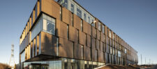 Side view of Québec City Central Police Station with large glass partitions and bronze cladding.
