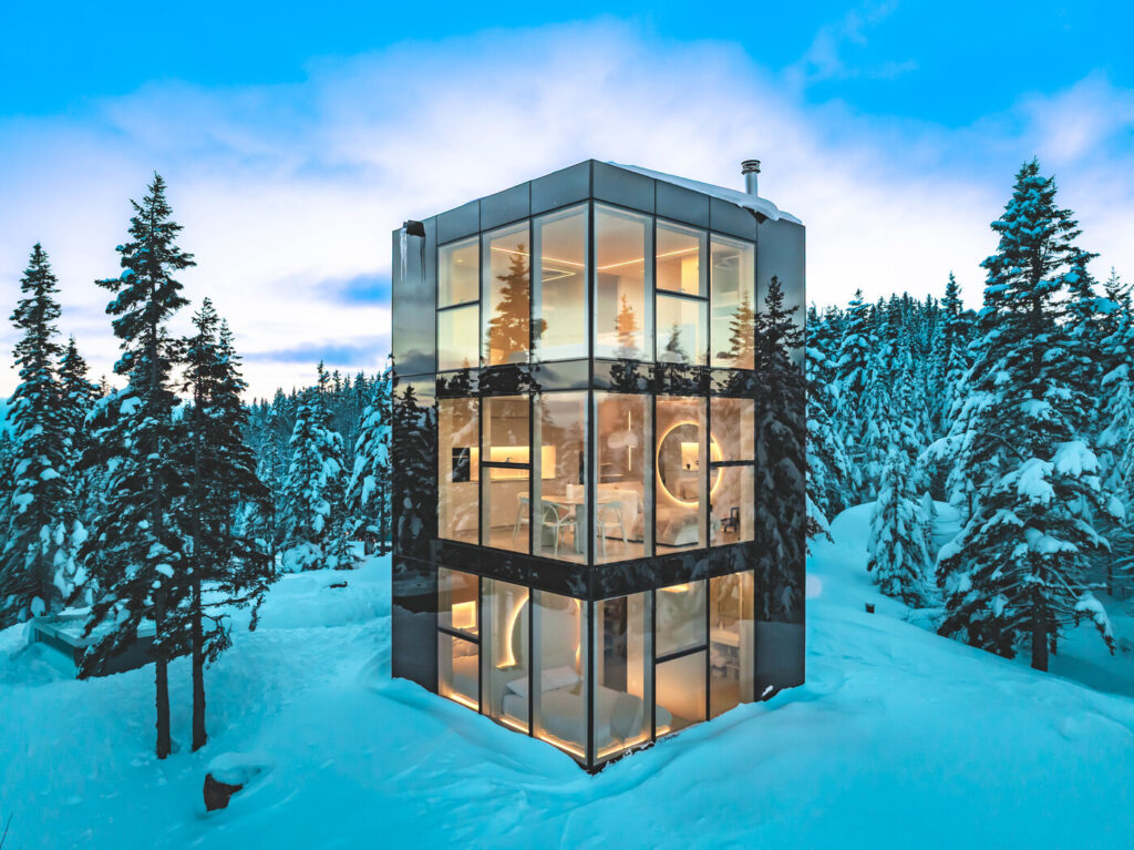 Chalet Black Mirror illuminé en hiver avec façade miroir Multifacades et grandes fenêtres sur trois niveaux