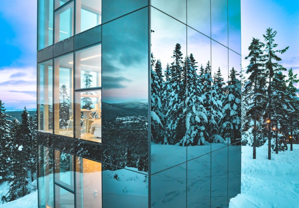 Angle rapproché du chalet Black Mirror avec vitrages pleine hauteur et façade miroir Multifacades STEKAR