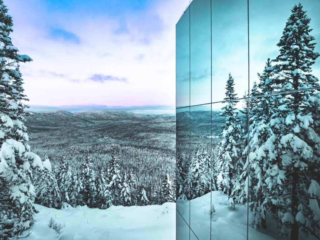 Détail de la façade miroir Multifacades du chalet Black Mirror reflétant la forêt enneigée