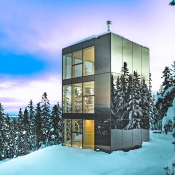 Micro-chalet Black Mirror avec façade miroir Multifacades STEKAR au cœur d’une forêt enneigée