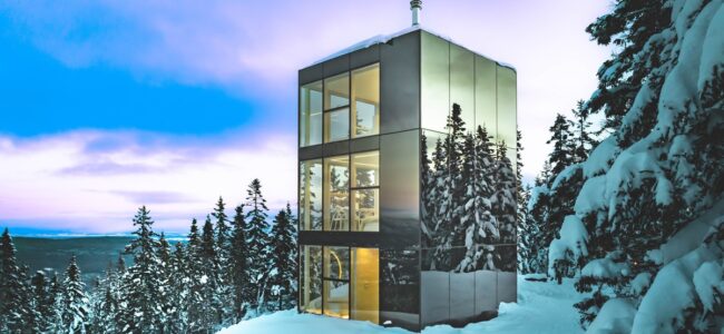 Micro-chalet Black Mirror avec façade miroir Multifacades STEKAR au cœur d’une forêt enneigée